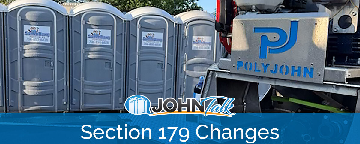 A closeup of a slide-in vacuum unit on a truck with a row of gray portable toilets in the background
