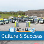 A lineup of portable toilet service trucks in a parking lot with two gray and lime portable toilets in front of them
