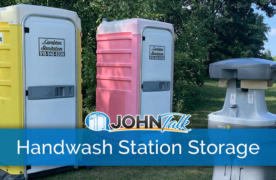A portable handwash station and two portable toilets, one yellow and white and one pink and white, in a lush, green setting