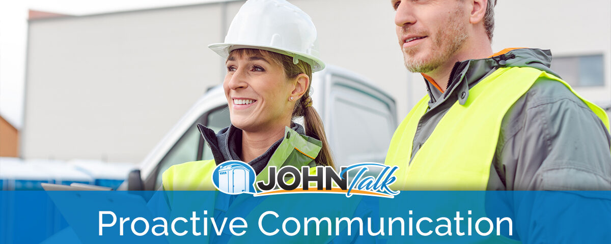 Two workers wearing hard hats and high-vis vests with a truck in the background