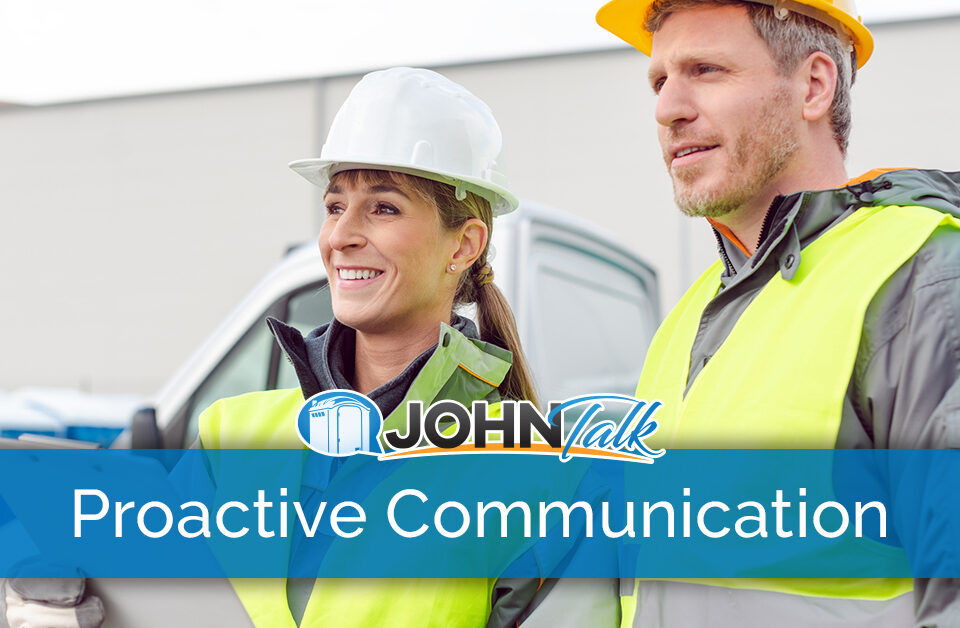 Two workers wearing hard hats and high-vis vests with a truck in the background
