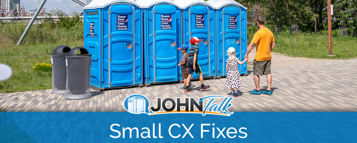 A man and three children stand outside a row of blue portable toilets