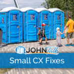 A man and three children stand outside a row of blue portable toilets