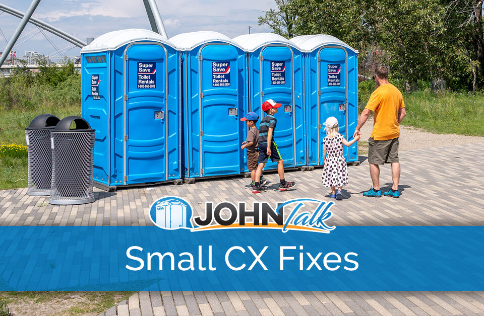 A man and three children stand outside a row of blue portable toilets