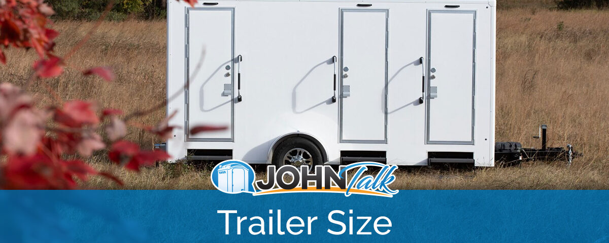 A white portable restroom trailer sitting in a grassy area